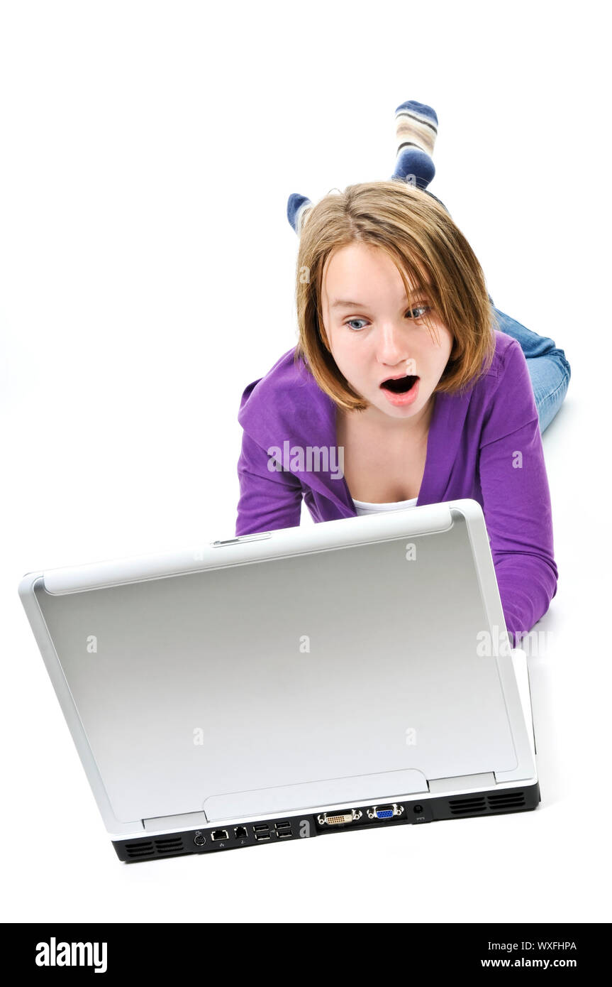 Surprised young girl lying down with laptop computer Stock Photo