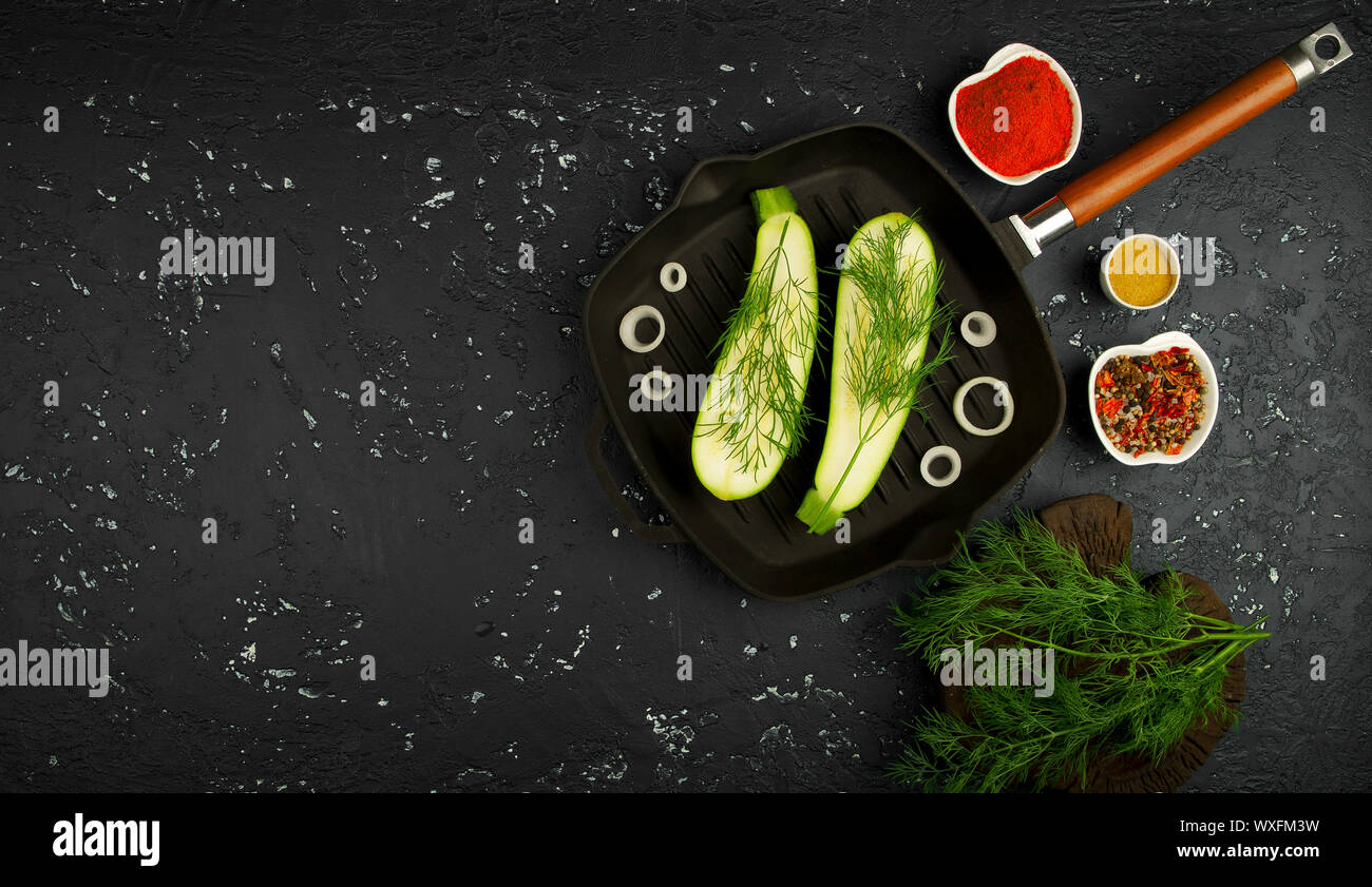 Fresh green zucchini in a pan on a dark table. The view from the top. Copy space. Stock Photo