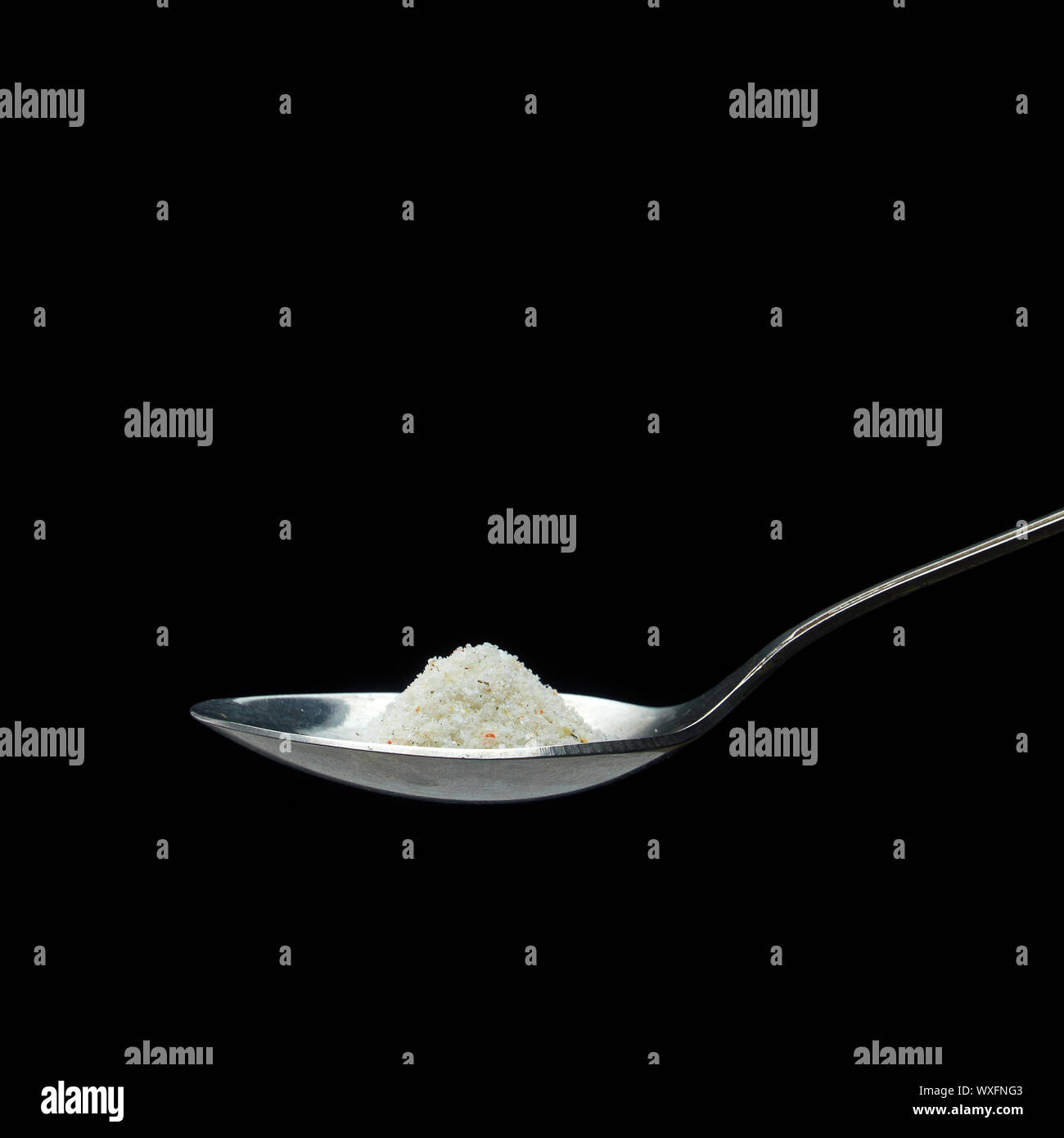 A LARGE SPOON OF SALT OR SEASONING ON A DARK BACKGROUND Stock Photo