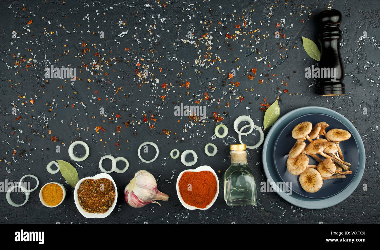 Fresh mushrooms with spices and herbs on black board. View from above ...