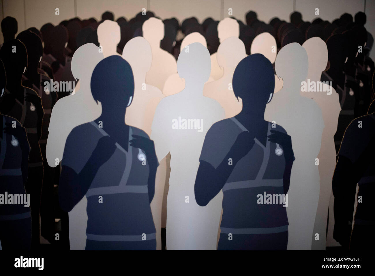 100 lifesize cardboard cutouts of nurses, with 11 blanked out to