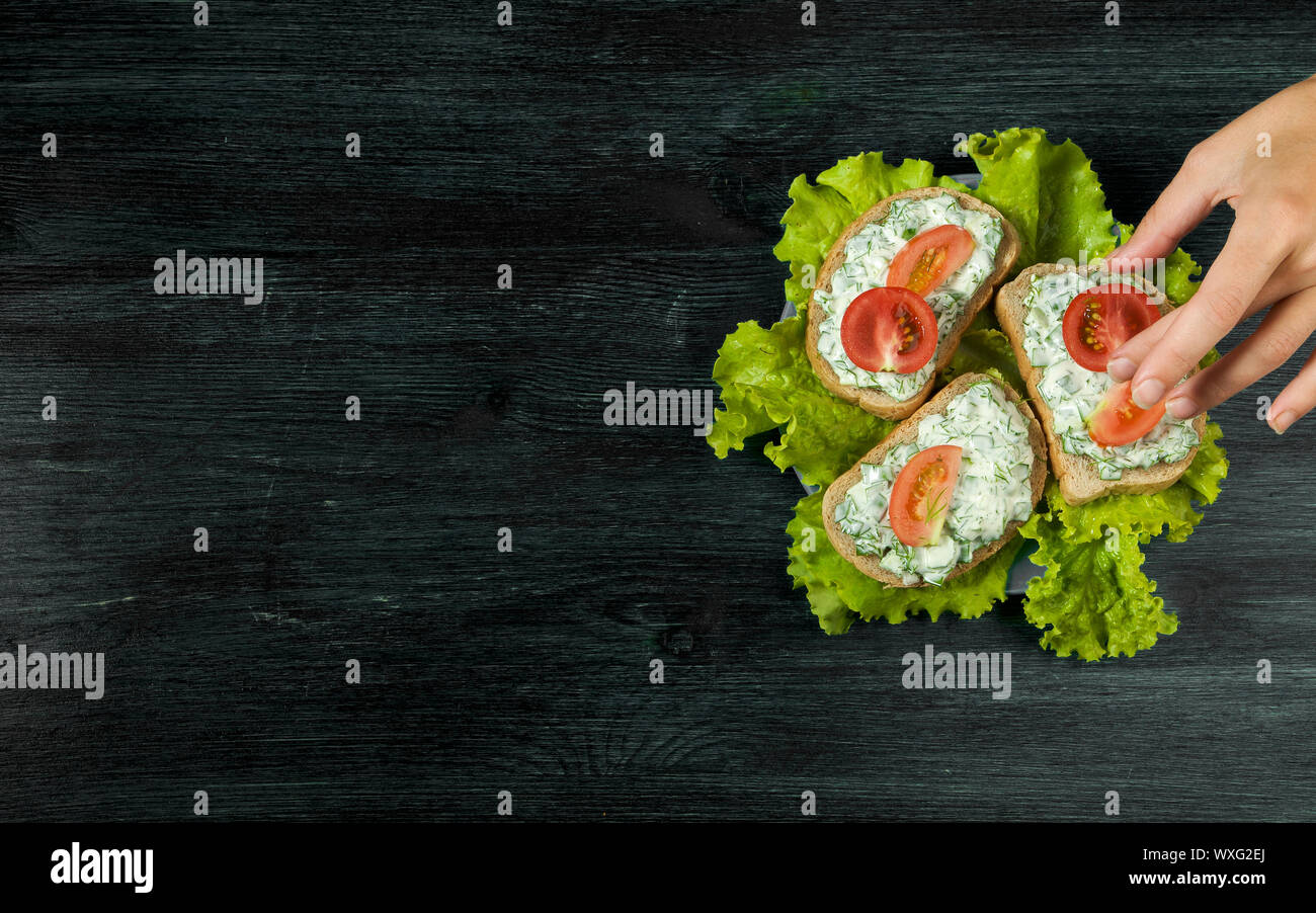 Sandwiches with vegetables. Fresh sandwiches with vegetables on a dark board on a textured background. View from above. Copy spa Stock Photo