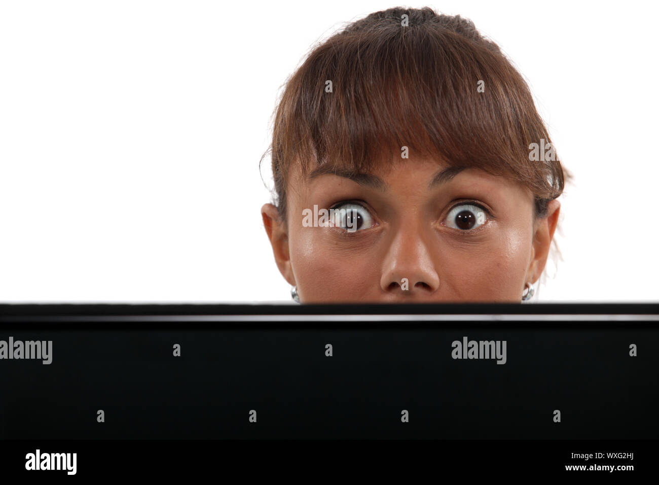 Woman Head Over Computer Screen Wide-eyed woman peering over her laptop Stock Photo - Alamy