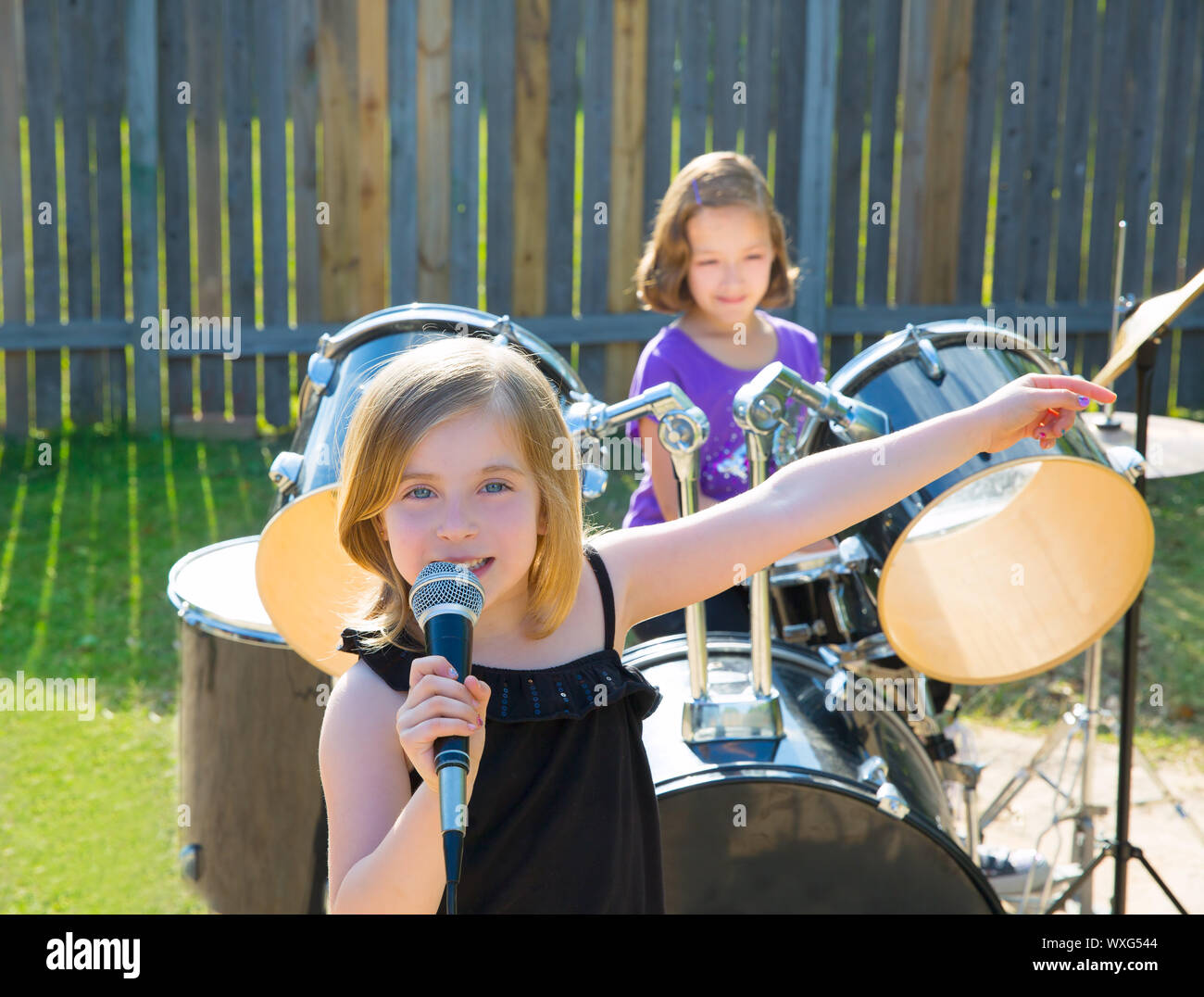 Blond kid singer girl singing playing live band in backyard concert with friends Stock Photo