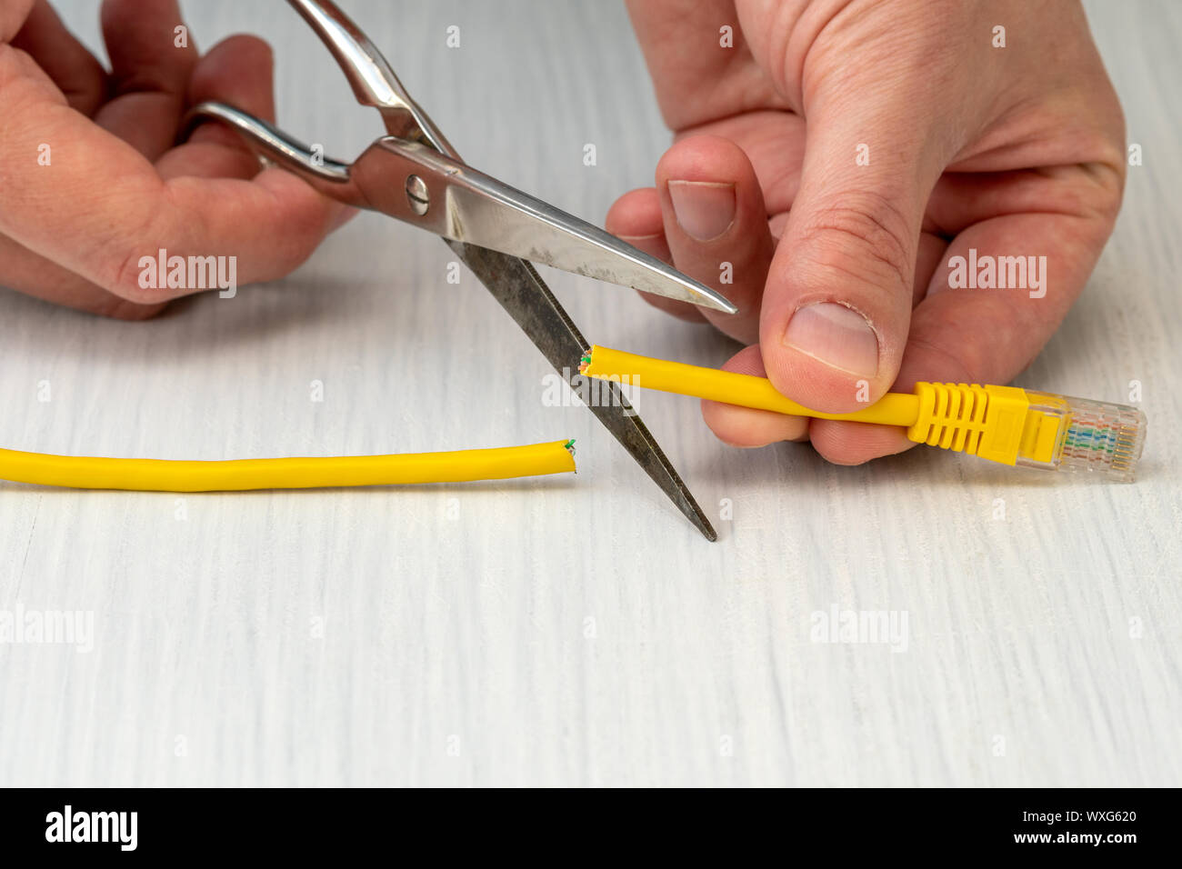 Internet censor cutting a yellow network cable with scissors.Restricted internet access concept Stock Photo
