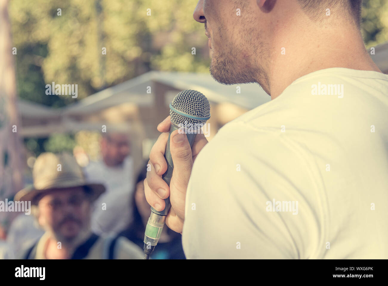 Man delivering a speach in front of live audience outdoor. Summer events in city. Stock Photo