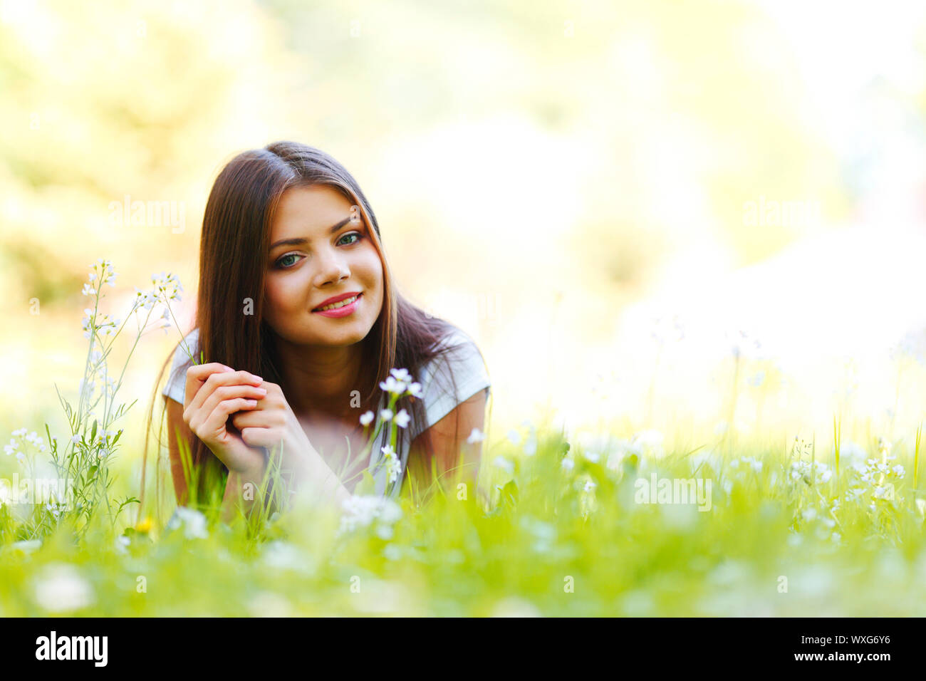 Beautiful young woman lying on grass with flowers Stock Photo - Alamy