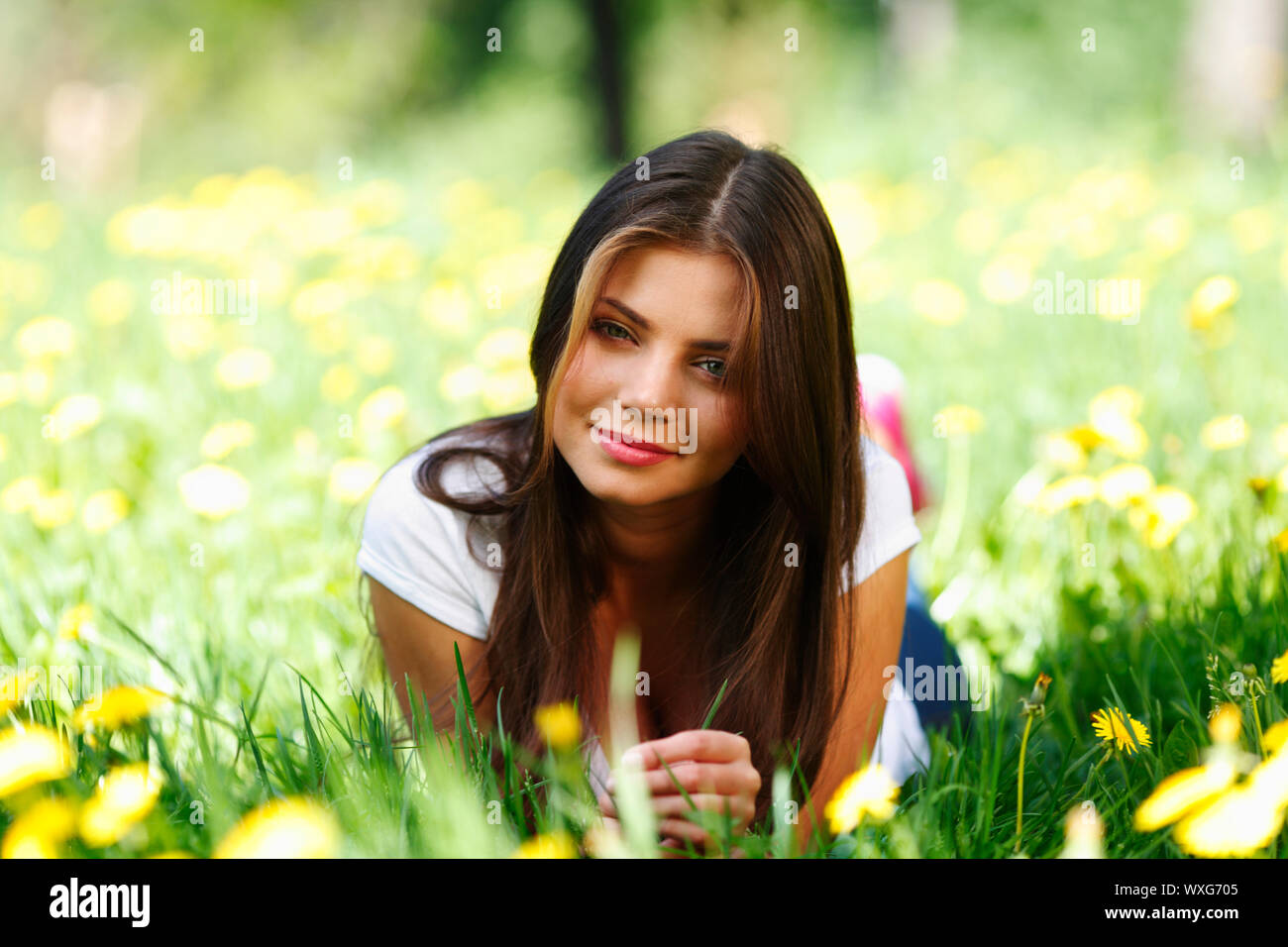 Beautiful young woman lying on grass with flowers Stock Photo - Alamy