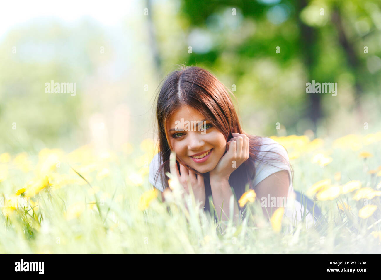 Beautiful young woman lying on grass with flowers Stock Photo - Alamy