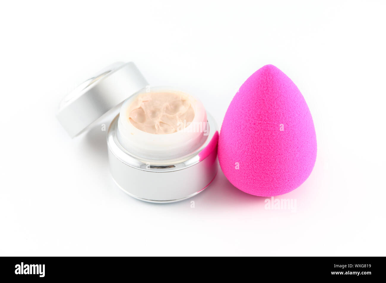 Open jar of cosmetic face cream with an applicator sponge at the side