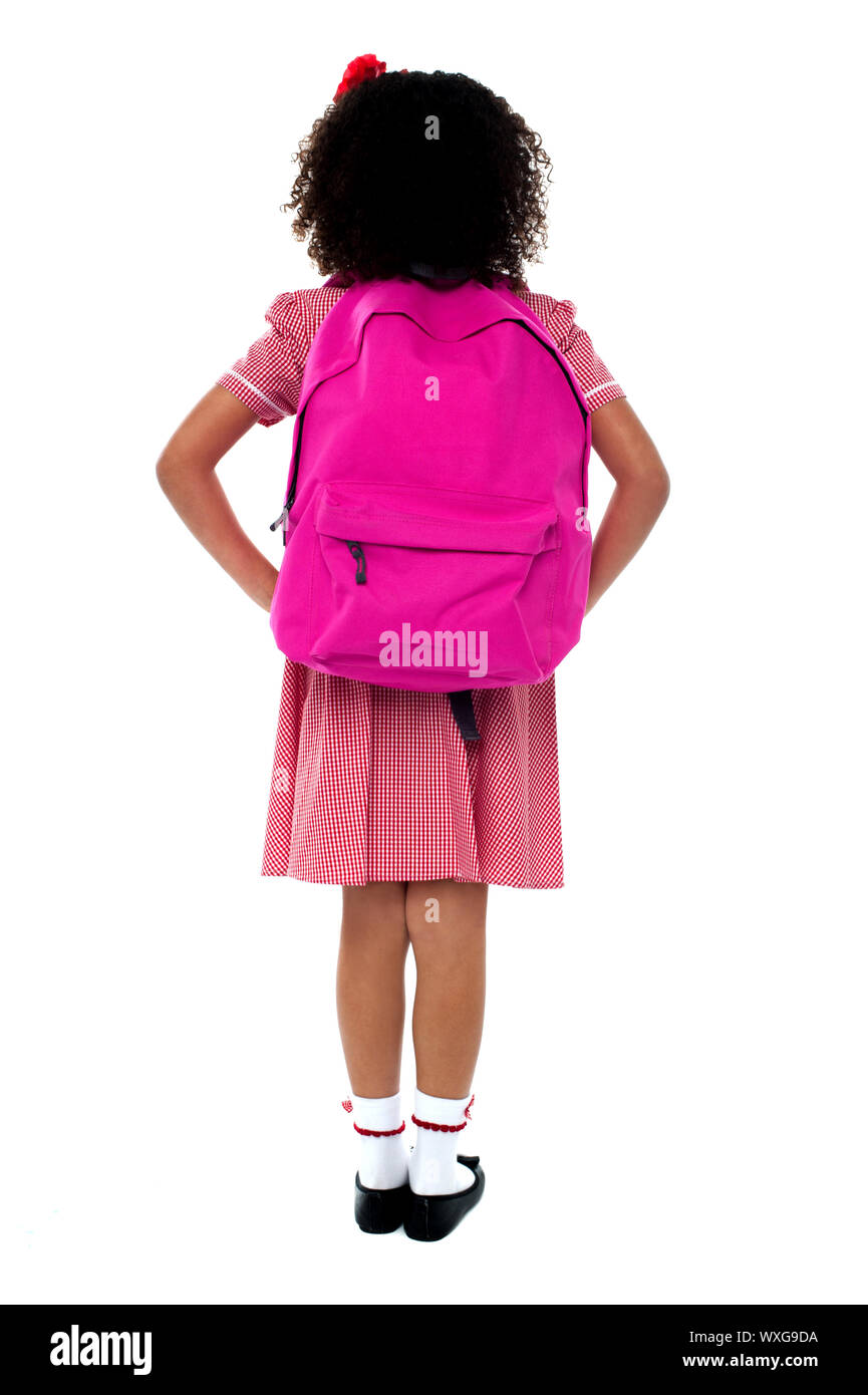 Primary school girl in uniform with school bag over shoulder over white