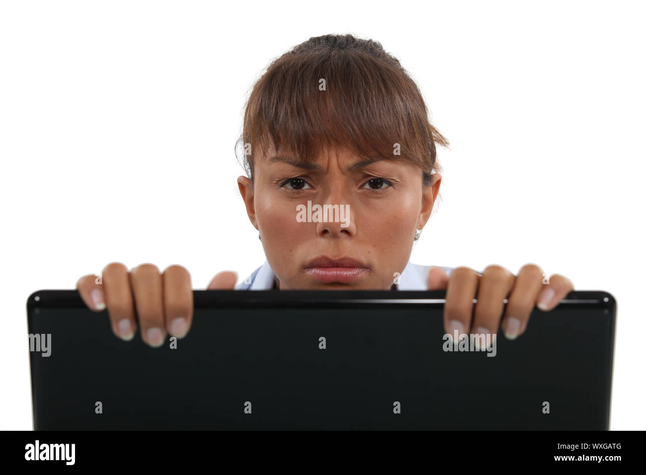 Displeased businesswoman peering over laptop Stock Photo