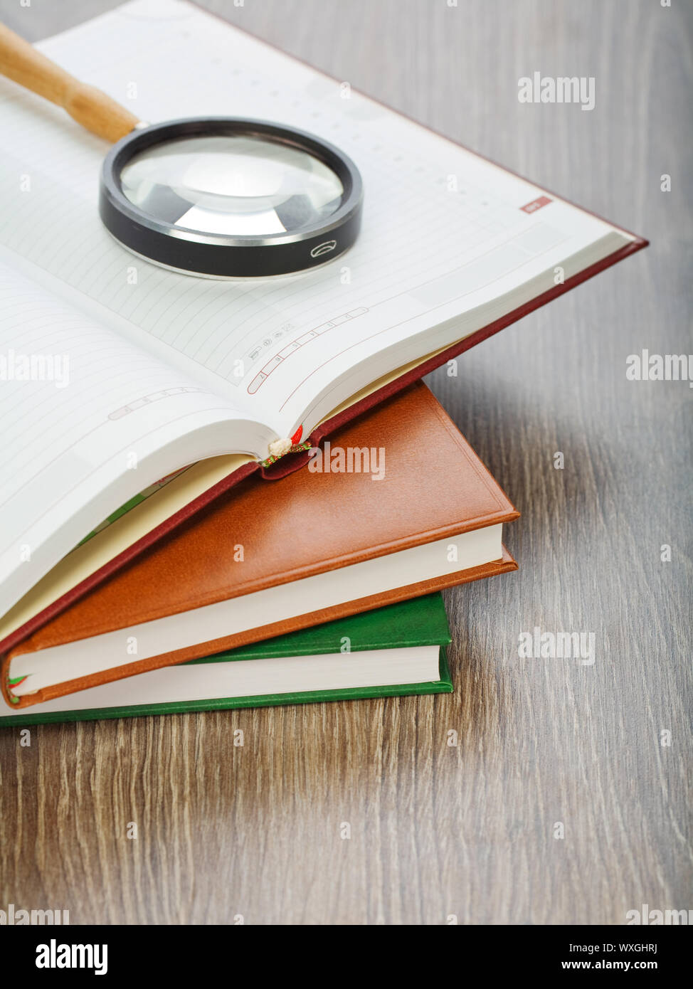 diaries and magnifier on wooden background Stock Photo