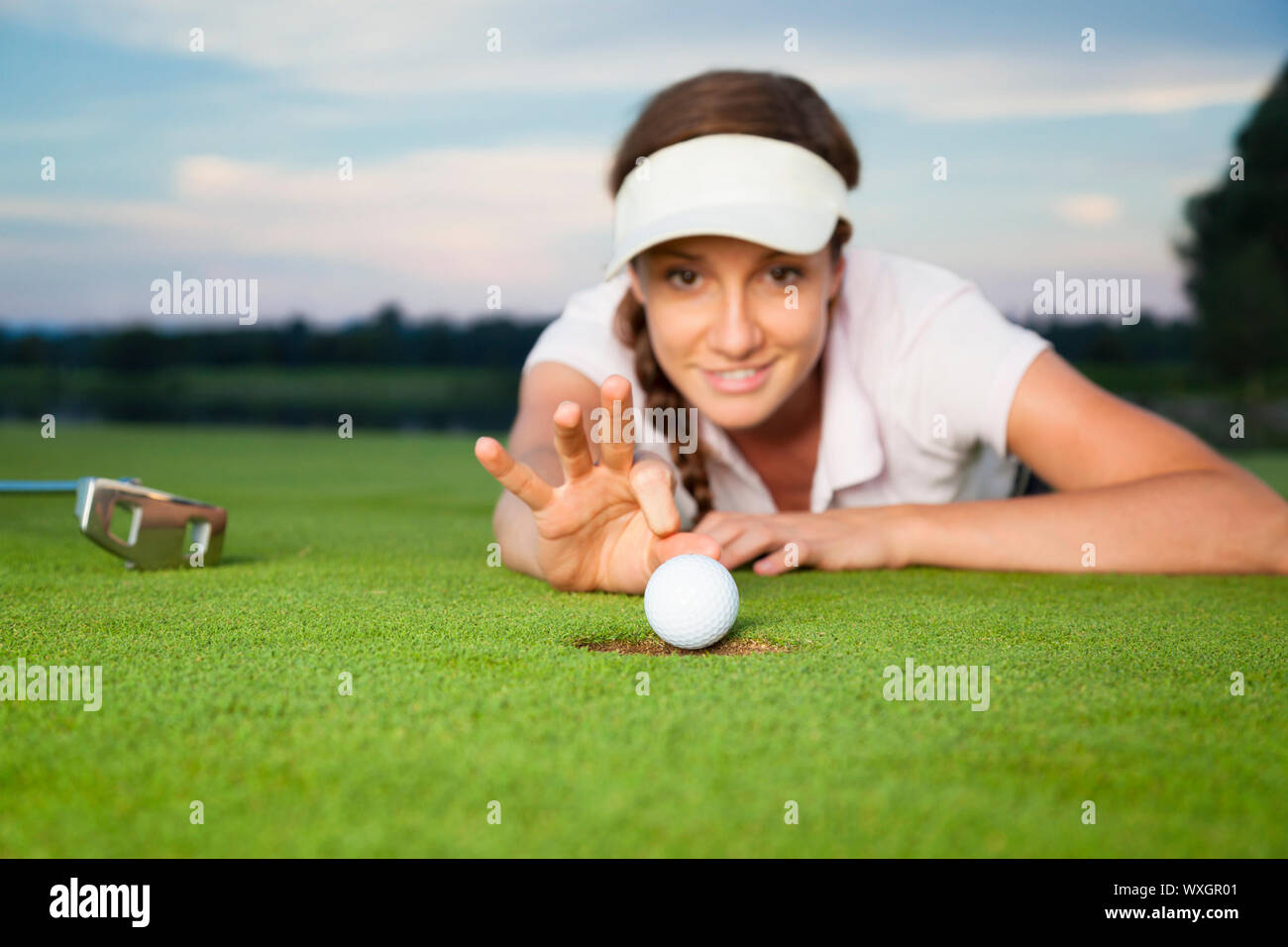 Girl golfer making a trick on green. Stock Photo