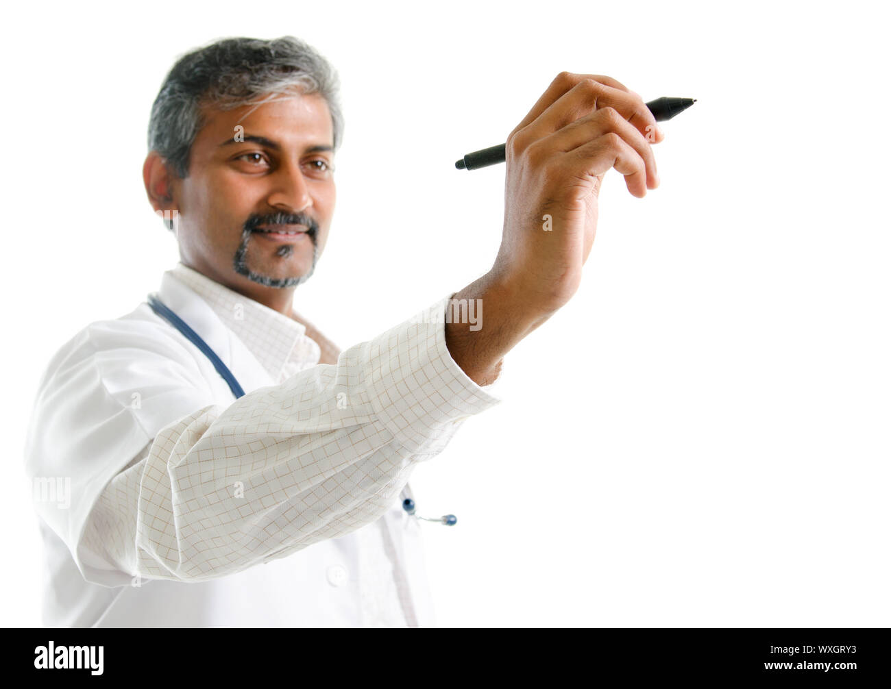 Indian doctor writing. Mature Indian male medical doctor drawing or sketching on blank space, standing isolated on white background. Handsome Indian m Stock Photo