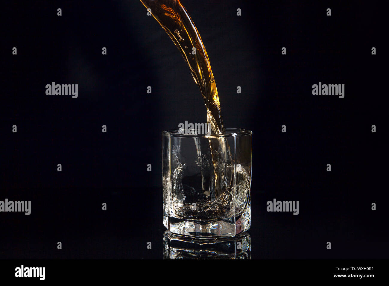 https://c8.alamy.com/comp/WXH0R1/whiskey-pouring-into-glass-with-ice-isolated-on-reflective-black-surface-whiskey-splash-out-of-glass-many-drops-of-beverage-get-out-from-glass-WXH0R1.jpg