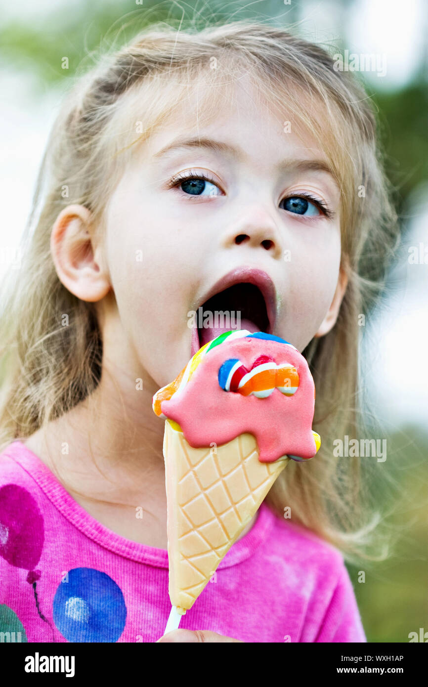 Little girl licking a sucker that is in the shape of an ice cream cone. Stock Photo
