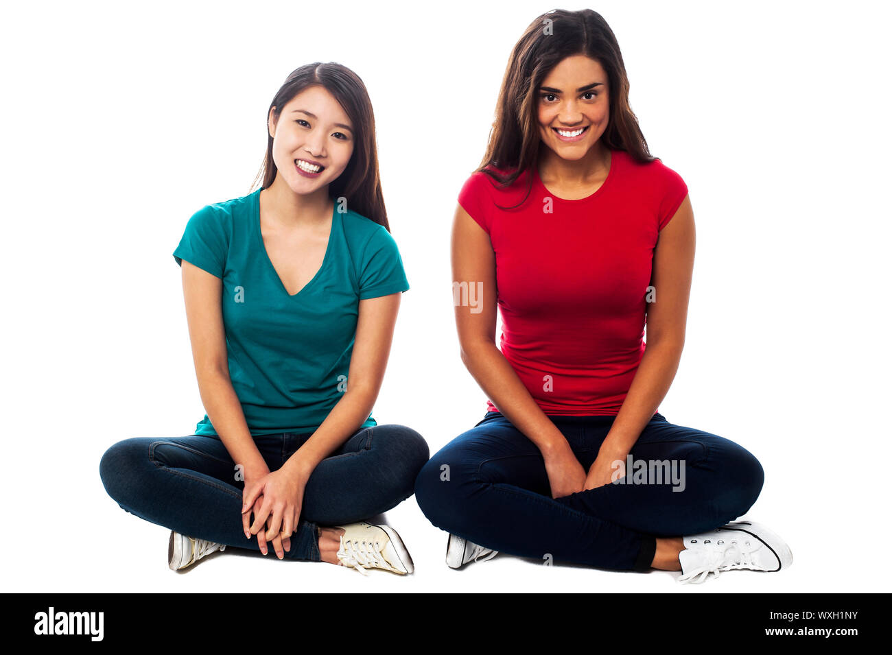 Two young girls sitting on the floor, legs crossed Stock Photo - Alamy