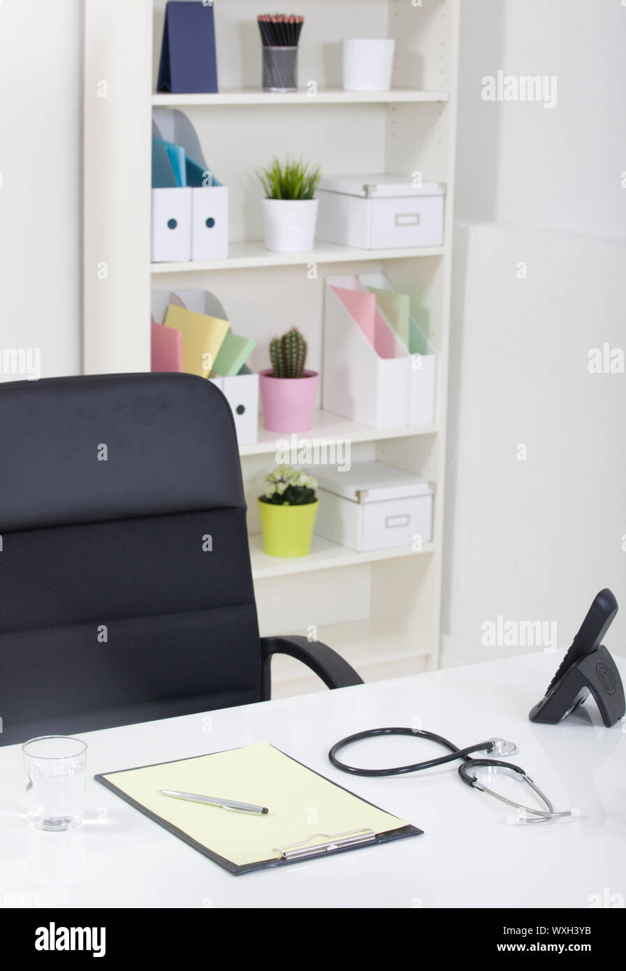 Doctor office table desk and black chair with stethoscope and white