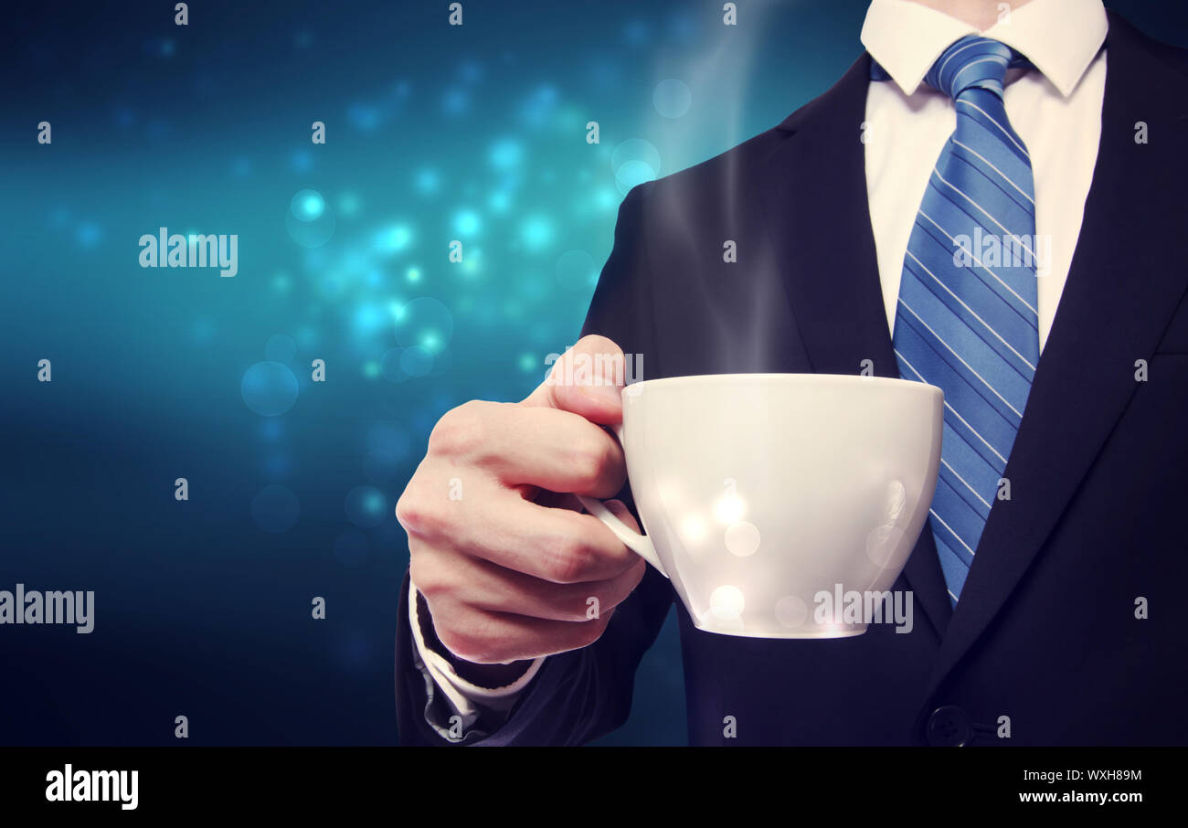 Business man holding a steaming cup of hot coffee on blue modern background Stock Photo