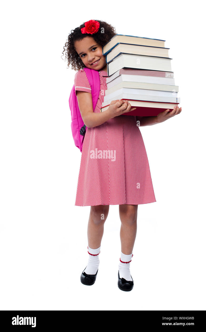 Smiling little girl holding pile of school books Stock Photo - Alamy