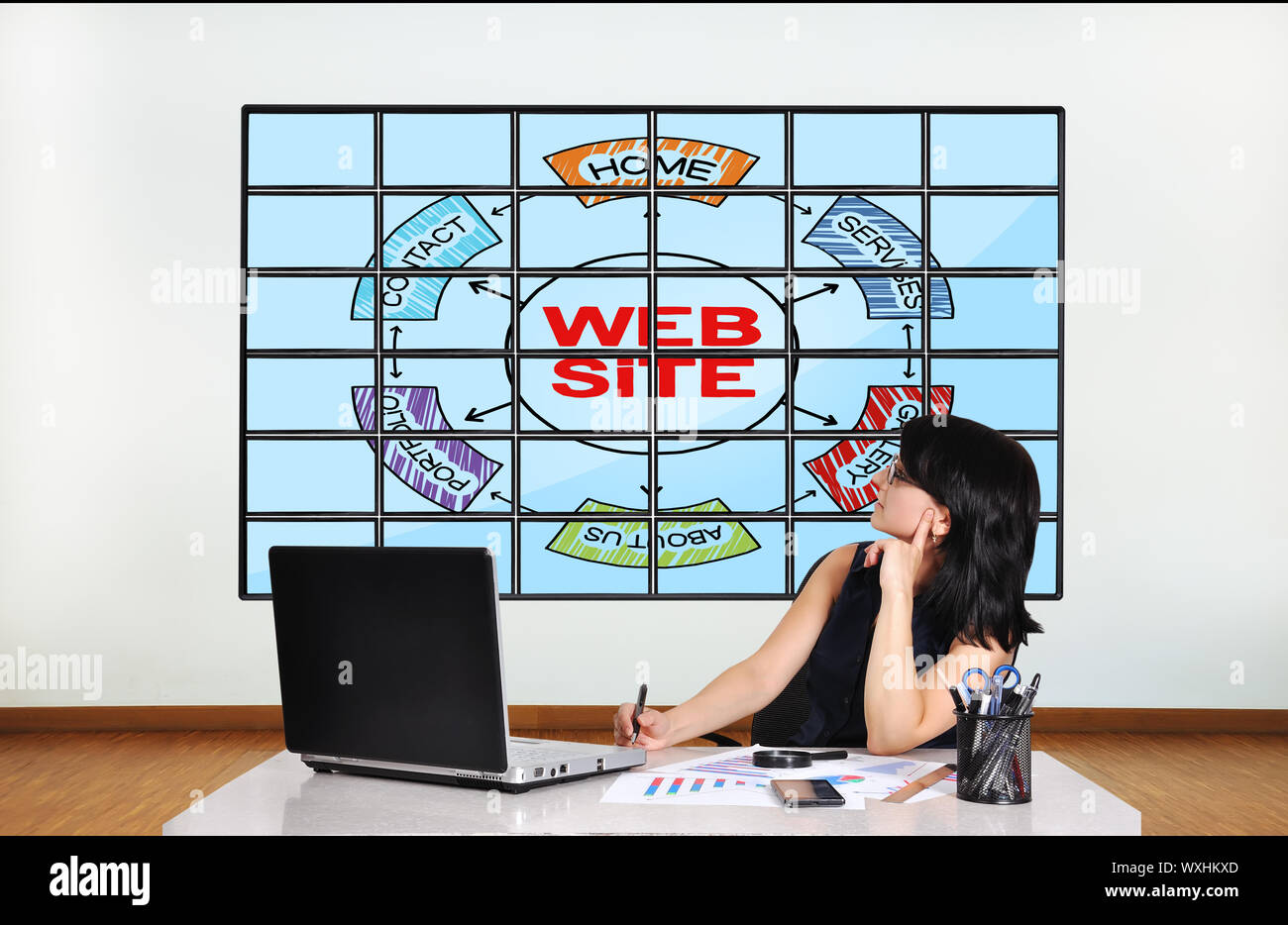 woman in office looking at plasma with web site scheme Stock Photo