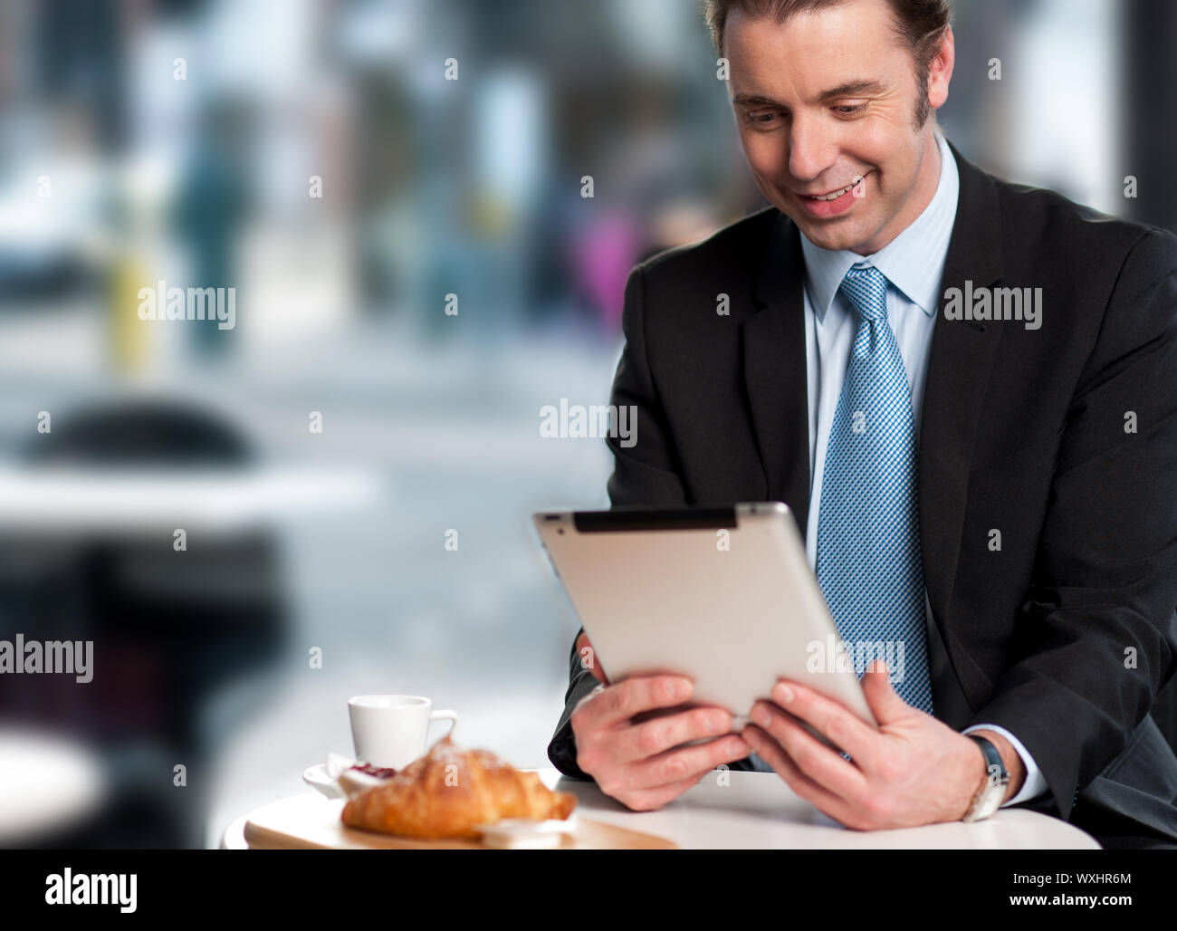 Corporate male manager reviewing business updates on his tablet device. Stock Photo