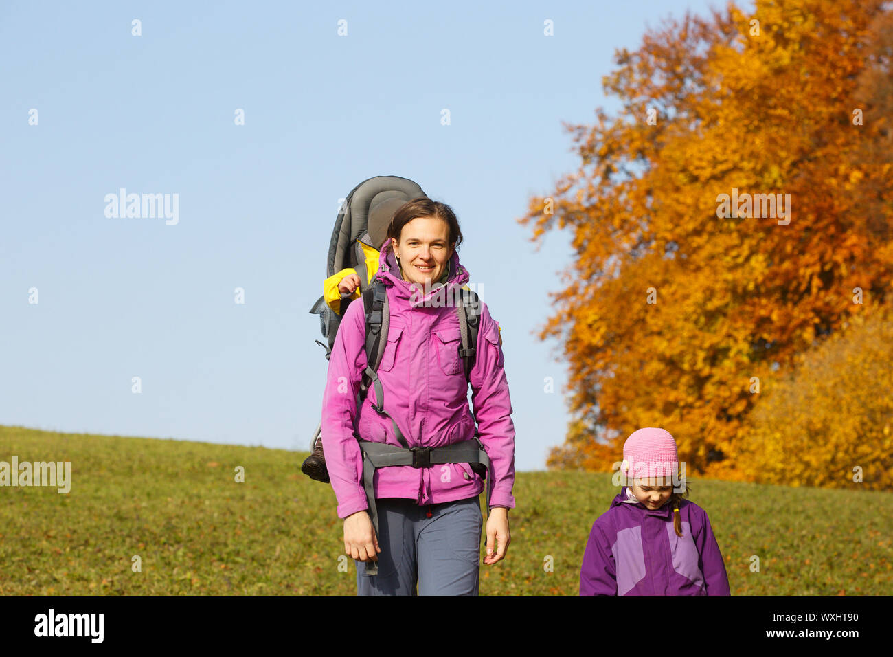 Mother with children in nature on a nice autumn day carrying kid Stock Photo