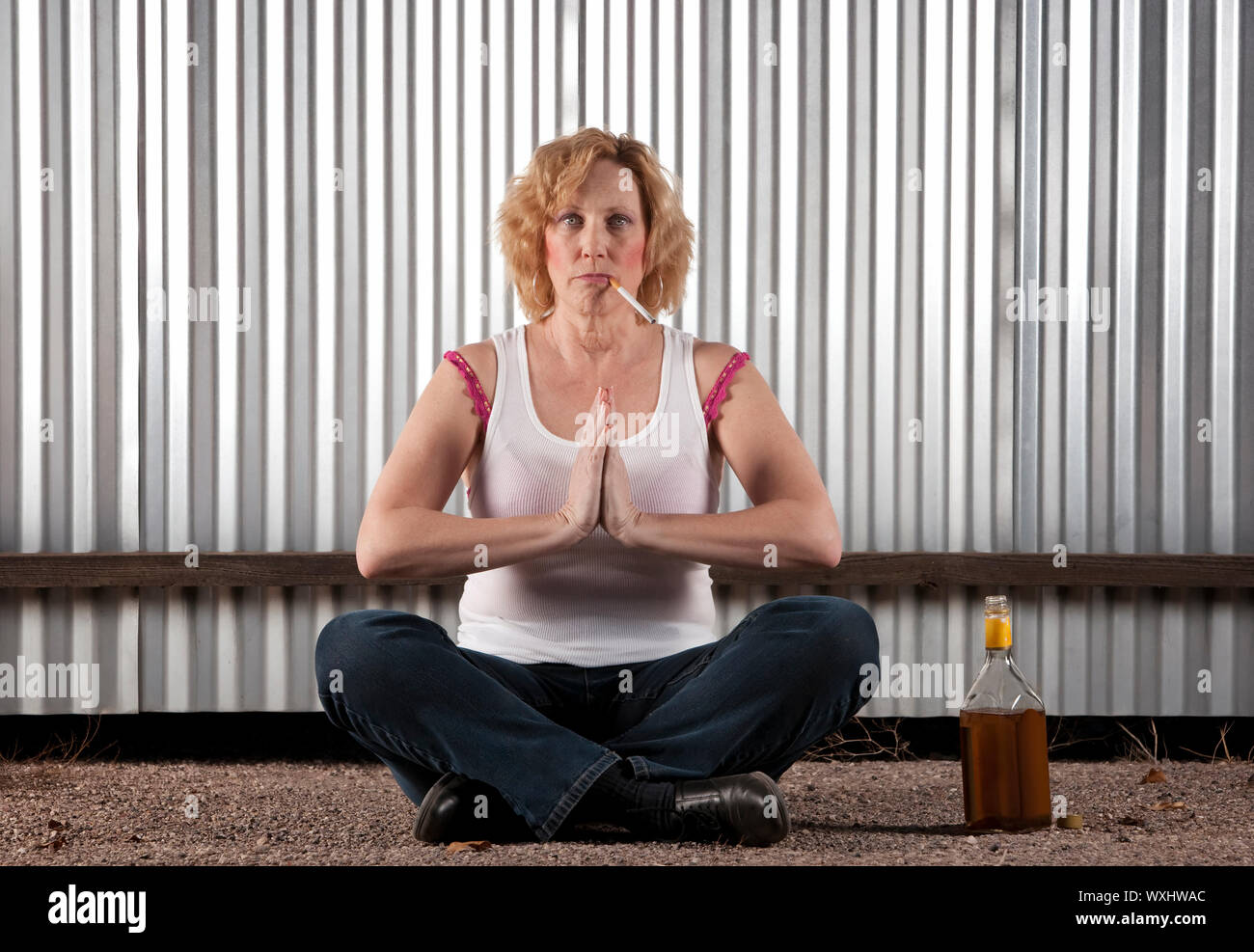 Woman meditating with cigarette and tequila bottle Stock Photo