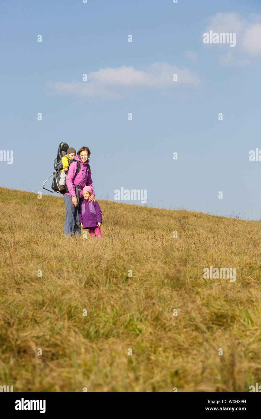 Mother with children in nature on a nice autumn day carrying kid Stock Photo
