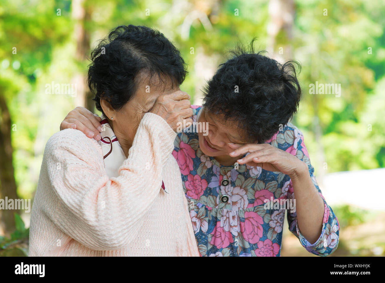 Sad senior Asian women  in grieving the loss of a loved one. Outdoor park. Stock Photo