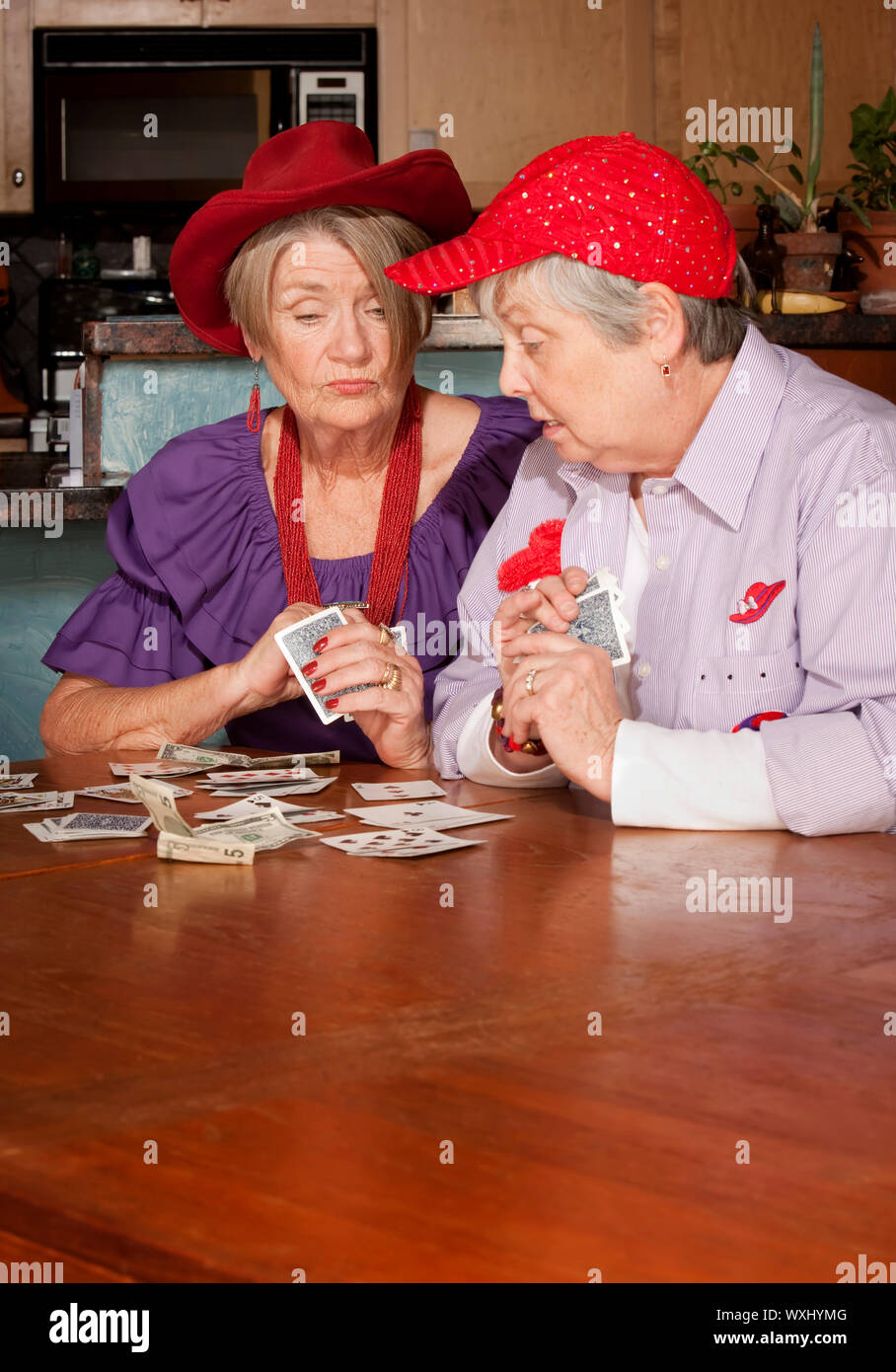 Ladies wearing red hats playing a hand of cards Stock Photo - Alamy