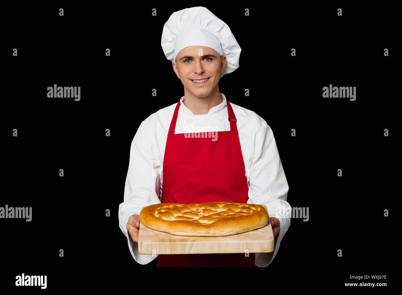 Isolated chef holding bread, black background. Stock Photo