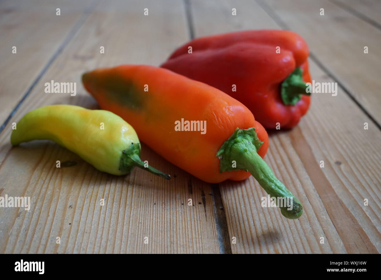 Set of multicolored sweet peppers on a rustic wooden table Stock Photo