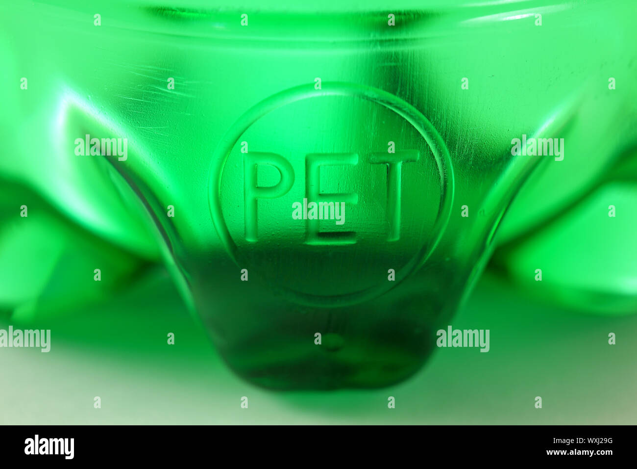 Very nice detail of green plastic sparkling water bottle placed on glass with beautiful reflections of light for an elegant and abstract effect Stock Photo