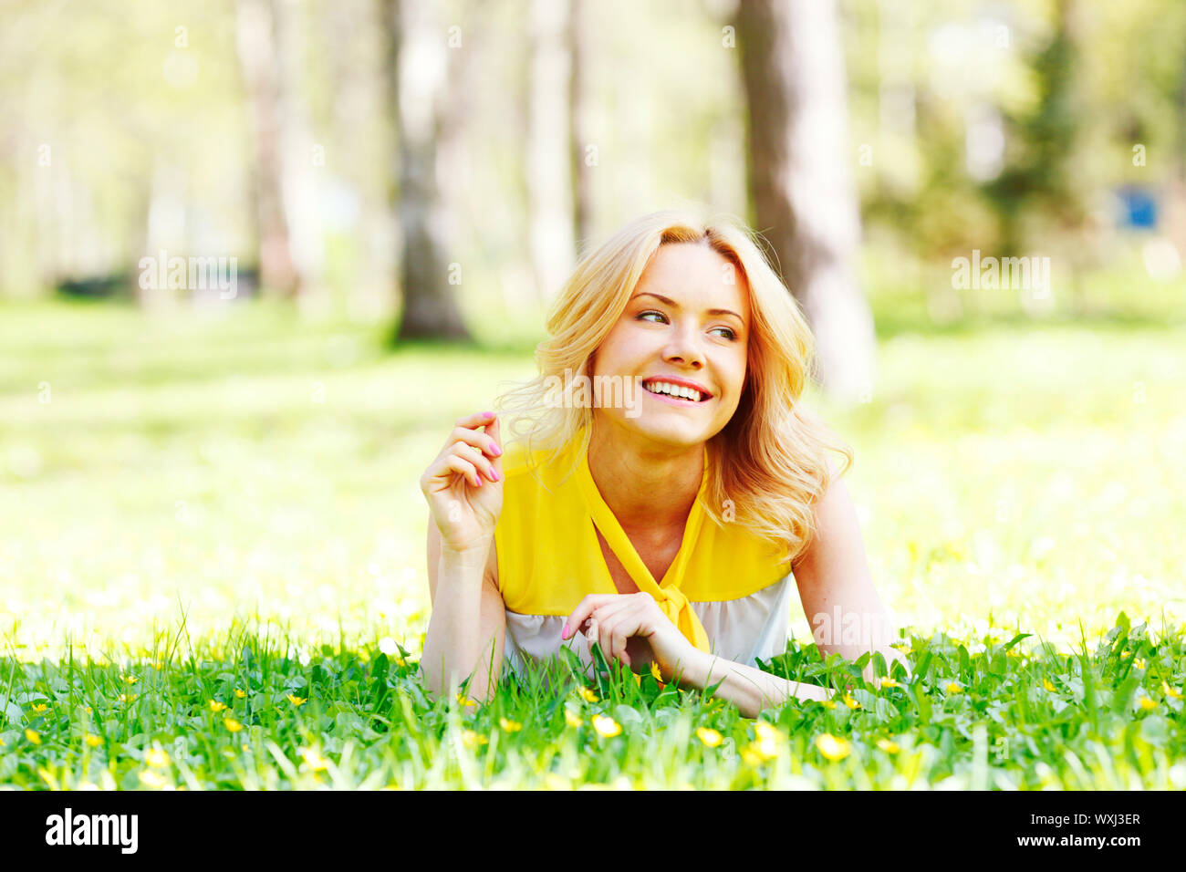Happy young woman lying on grass Stock Photo - Alamy