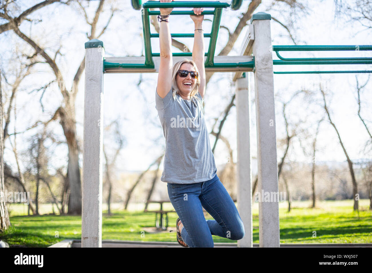 Woman hanging from monkey bars in a playground, United States Stock Photo