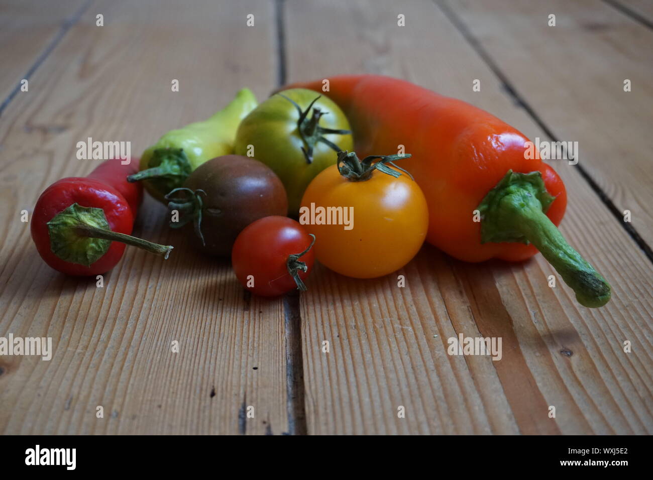 Set of multicolored long peppers and heirloom tomatoes on a rustic ...