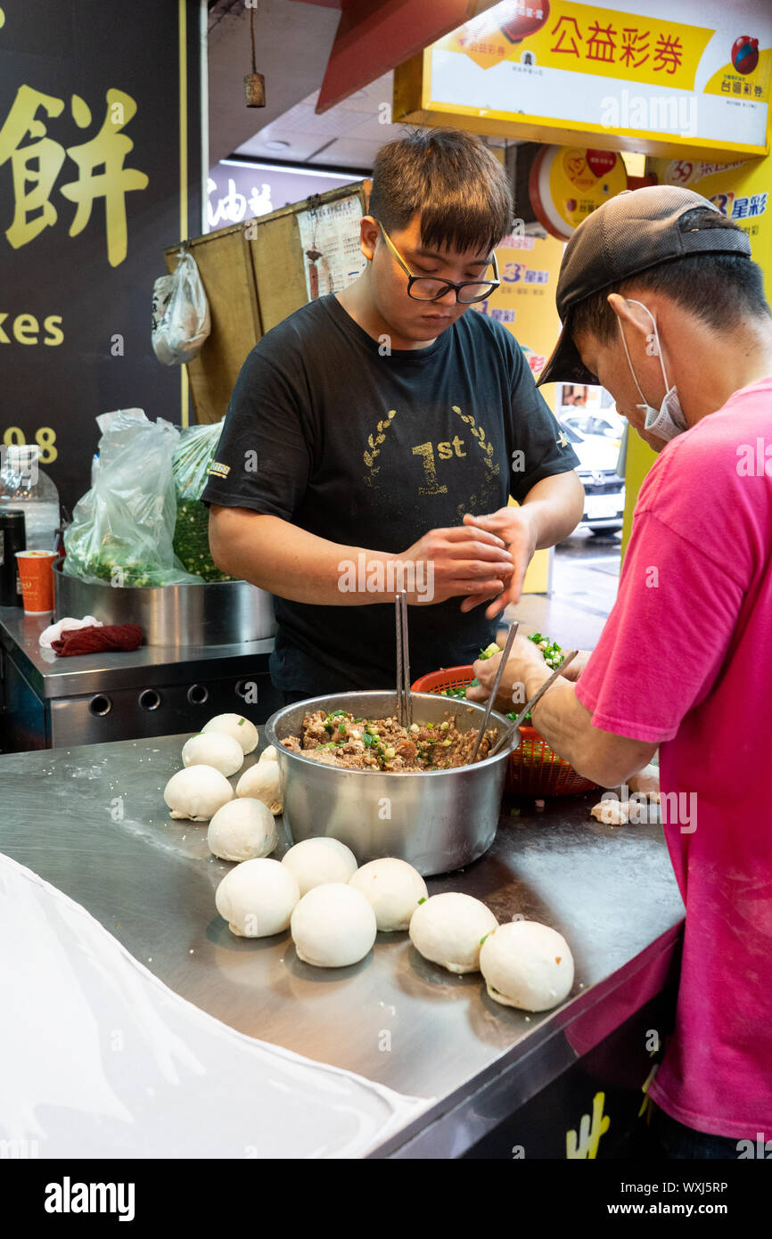 Men are preparing a traditional chinese / taiwanese snack called Hu Jiao Bing or Pepper Pork Buns. Buns filled with Pork backed in a Tandoori Style Stock Photo