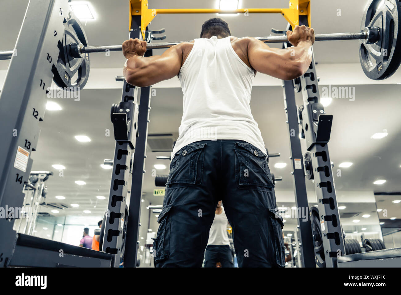 Man at the gym. Execute exercise squatting with weight, in gym Stock Photo