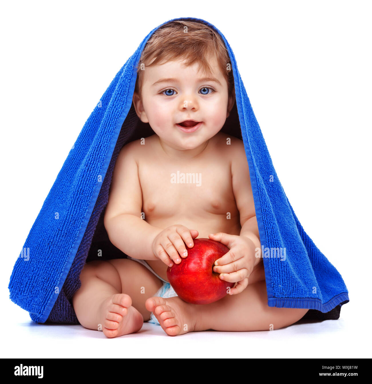 Cute baby boy covered with blue towel holding in hands red fresh ...