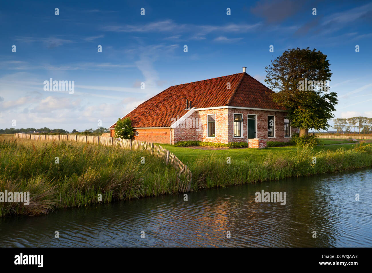 charming farmhouse by river in sunlight Stock Photo - Alamy