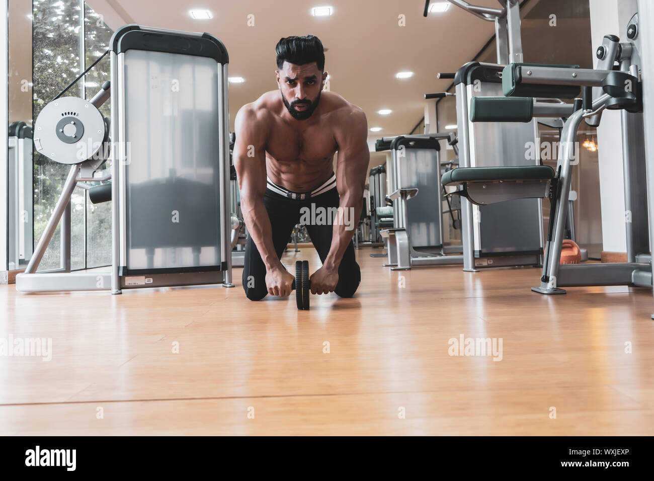 Athlete sporty man doing exercise with abs roller wheel to strengthen
