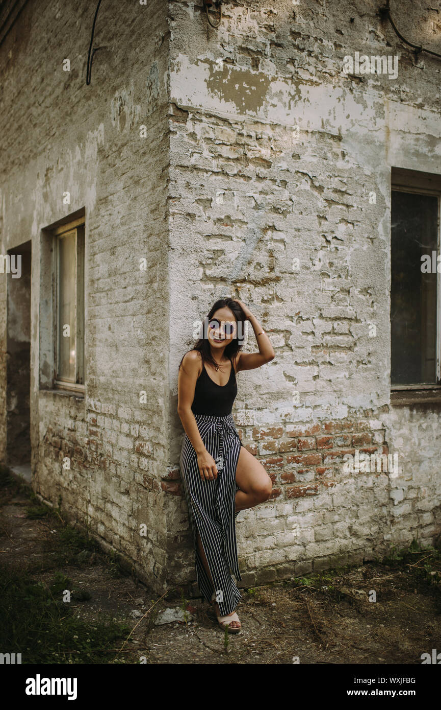 Portrait of a young woman standing in front of a brick wall Stock Photo ...
