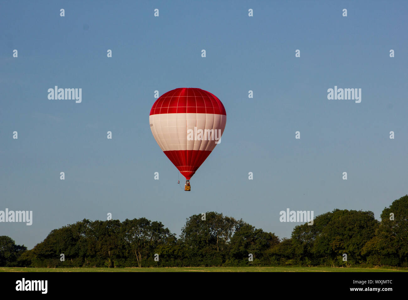 A perfect red and white stripey hot air balloon flying against and ...