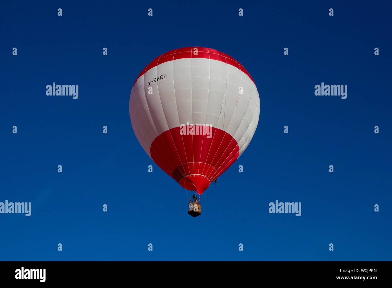A perfect red and white stripey hot air balloon flying against and ...