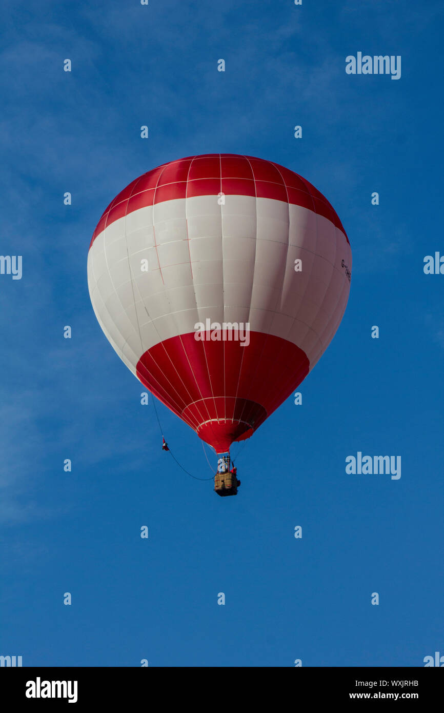 A perfect red and white stripey hot air balloon flying against and ...