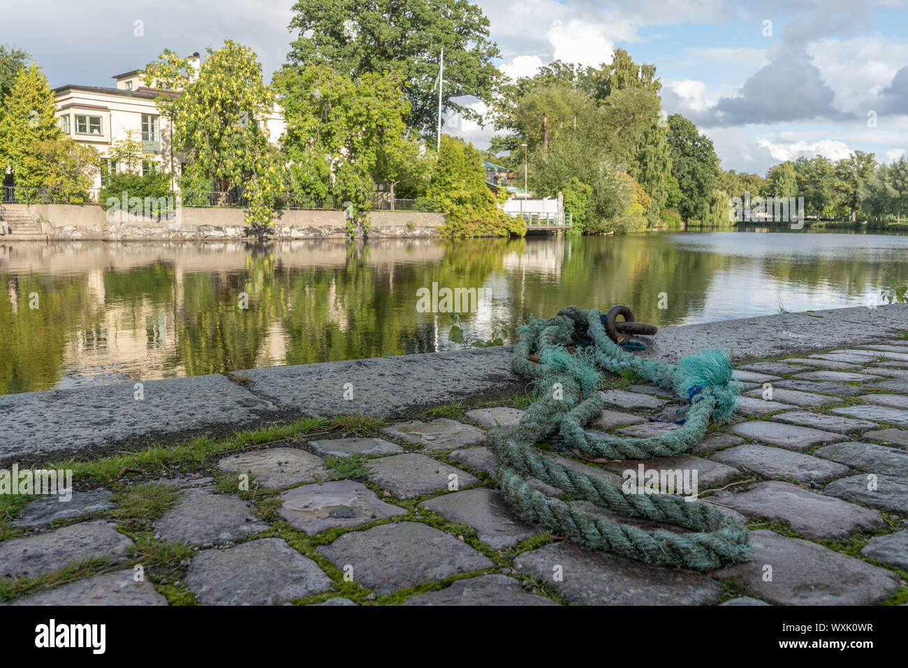 Old, green rope lies on rocky street by river. Orebro city center. Travel photo, background image or illustration. Stock Photo