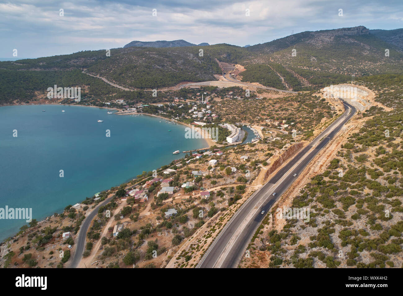 Mountain highway road, nautical vessels in the sea harbor and pinecovered mountain ranges in