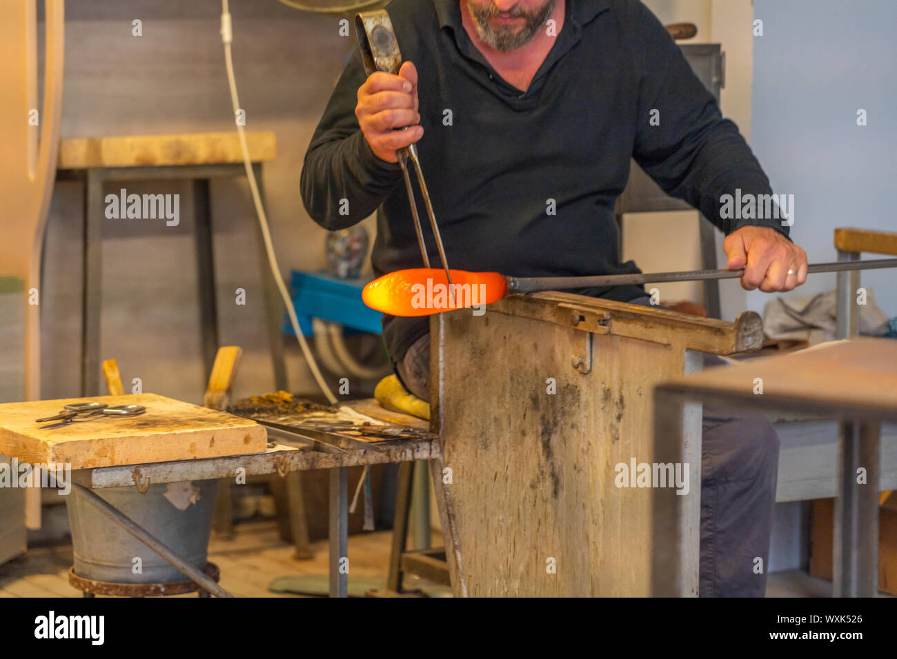 Glass blowing artist working on high temperature flame at workshop ...